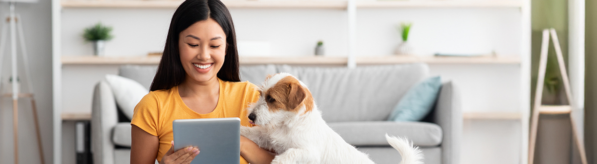 Woman smiling with her dog on her tablet researching social research solutions relevant to audiences.